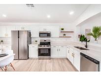 Bright kitchen with stainless steel appliances, white cabinets, and quartz countertops offers a modern design at 2030 S 86Th Dr, Tolleson, AZ 85353