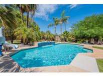 Beautiful backyard pool featuring palm trees and a built-in water feature, perfect for relaxation and entertainment at 2160 E Kenwood St, Mesa, AZ 85213