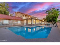 An inviting pool reflects the lovely sunset sky surrounding this beautiful brick home at 6550 N 7Th St, Phoenix, AZ 85014