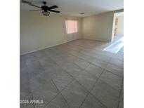 Bright living room with tiled floors and ceiling fan at 1352 S 221St Ln, Buckeye, AZ 85326