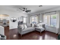 Bright living room featuring a gray sectional sofa, hardwood floors, and large windows with natural light at 12107 N 66Th Ave, Glendale, AZ 85304