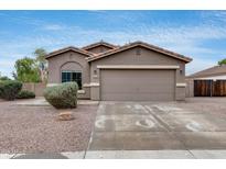 Charming single-story home features a two car garage, desert landscaping, and a welcoming facade under a blue sky at 16103 W Redfield Rd, Surprise, AZ 85379