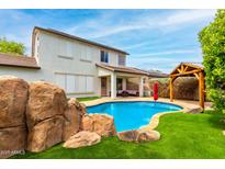 Stunning backyard with a rock feature by the pool, gazebo and covered patio with comfortable outdoor seating at 18171 W Marshall Ln, Surprise, AZ 85388