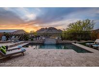 Beautiful backyard pool with water feature, lounge chairs, and mountain views at sunset at 27276 N 81St Ln, Peoria, AZ 85383