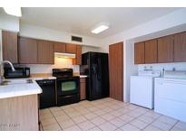 Cozy kitchen featuring tiled floors, brown cabinetry, and black appliances at 4625 W Thomas Rd # 71, Phoenix, AZ 85031