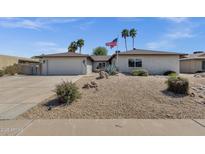 Charming single-story home featuring desert landscaping, palm trees, and American flag at 4913 E Acoma Dr, Scottsdale, AZ 85254