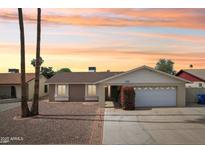 Charming single-story home featuring a two-car garage, brick accents and beautiful desert landscaping at sunset at 638 W Pantera Ave, Mesa, AZ 85210