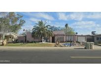 Charming pink home featuring a palm tree, fountain, and rock accents in its welcoming front yard at 6725 W Colter St, Glendale, AZ 85303