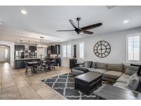 Open concept living room with gray sectional, stylish rug, kitchen island and dining table at 7634 W Redbird Rd, Peoria, AZ 85383