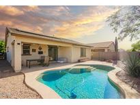 Backyard pool with a table and chairs under a covered patio in a desert landscape and beautiful sunset at 16448 W Tether Trl, Surprise, AZ 85387