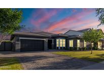Beautiful home exterior featuring a paved driveway and well-manicured lawn at dusk at 3145 E Boot Track Trl, Gilbert, AZ 85296
