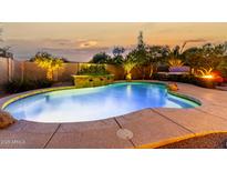 Beautiful pool with an elevated stone waterfall, lush landscaping, and an evening sky in the background at 3634 S Danielson Way, Chandler, AZ 85286