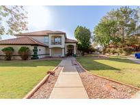 Inviting two-story home with lush green lawn, mature trees, and charming curb appeal at 2438 N Forest Cir, Mesa, AZ 85203