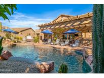 Inviting backyard pool and lounge area with covered patio and desert landscaping create a relaxing oasis at 3830 N Red Sky Cir, Mesa, AZ 85207