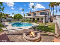 Inviting backyard featuring a sparkling pool, fire pit, green lawn, and mature landscaping perfect for outdoor living at 7469 E Timberlane Ct, Scottsdale, AZ 85258