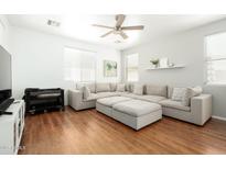 Bright living room featuring a large sectional sofa, wood floors, and a ceiling fan at 17613 N 114Th Ln, Surprise, AZ 85378
