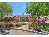 Charming home featuring a beautifully landscaped front yard with a brick walkway and flowering shrubs at 2013 E Solano Dr, Phoenix, AZ 85016