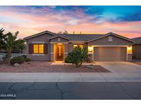 Charming single-story home featuring a two-car garage and desert landscaping against a colorful sunset sky at 20160 N Riverbank Rd, Maricopa, AZ 85138