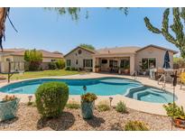 Resort-style backyard with a sparkling pool, spa, lush landscaping, and covered patio, perfect for entertaining and relaxation at 2222 W Morse Ct, Anthem, AZ 85086
