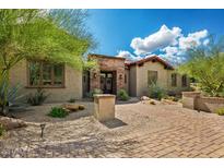 Inviting home featuring a beautiful front yard with mature landscaping, a brick walkway, and an attractive desert aesthetic at 37440 N 104Th Pl, Scottsdale, AZ 85262
