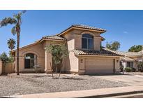 Charming home featuring a two-car garage, desert landscaping, and a classic Mediterranean-style tiled roof at 7239 E Madero Ave, Mesa, AZ 85209