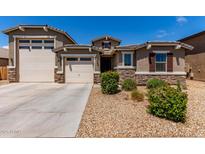 Charming single-story home with a well-manicured front yard, stone accents, and a three-car garage at 8010 W Atlantis Way, Phoenix, AZ 85043