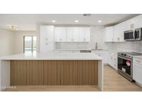Bright kitchen featuring white cabinets, gold hardware, stainless steel appliances, and a stylish island at 821 E Harmony Ave, Mesa, AZ 85204