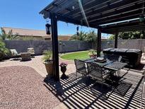 Outdoor living space featuring a pergola-covered patio, fire pit, and landscaped yard at 913 W Leadwood Ave, Queen Creek, AZ 85140
