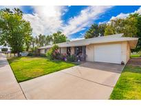 Single Gathering house with manicured lawn, mature plants, and a two-car garage at 17804 N Del Webb Blvd, Sun City, AZ 85373