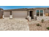 Charming single Gathering home featuring stone accents, brick driveway and well manicured desert landscaping at 18210 W Hess St, Goodyear, AZ 85338