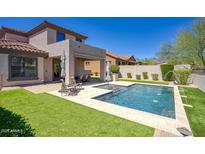 Inviting backyard features a pristine pool, manicured lawn, and covered patio, creating an ideal outdoor retreat at 18515 N 97Th Way, Scottsdale, AZ 85255