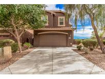 A two-story brown home with a two car garage and a well-manicured front yard at 20261 W Desert Bloom St, Buckeye, AZ 85326