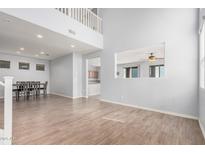 Bright, open living space with a two-story ceiling, wood-look tile floors and a view of the kitchen at 20261 W Desert Bloom St, Buckeye, AZ 85326