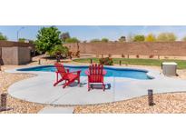 Relaxing backyard pool area with stylish red Adirondack chairs and ample space for outdoor entertaining at 6002 N 124Th Dr, Litchfield Park, AZ 85340