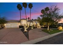 Elegant home featuring desert landscaping, a paver driveway, and a three-car garage at twilight at 11331 E Cochise Dr, Scottsdale, AZ 85259