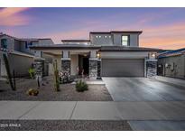 Two-story home featuring desert landscaping, a two-car garage, and a covered porch with stone accents at 16840 W Monroe St, Goodyear, AZ 85338