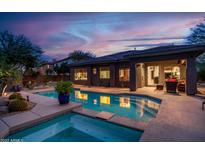 Backyard pool at dusk with blue lighting and patio at 2038 W Whisper Rock Trl, Phoenix, AZ 85085