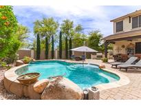 Beautiful backyard pool with fountain feature and lush landscaping at 42711 N 45Th Dr, Phoenix, AZ 85087