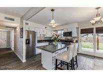 Bright kitchen features stainless appliances, modern finishes, an island with bar seating, and backyard access at 5801 W Cortez St, Glendale, AZ 85304