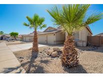 Charming single-story home with desert landscaping, palm trees, and spacious three-car garage at 16817 W Bradford Way, Surprise, AZ 85374