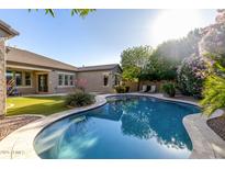 Sparkling backyard pool surrounded by lush, mature landscaping and a green yard at 22290 E Escalante Rd, Queen Creek, AZ 85142