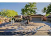 Charming single-story home with desert landscaping, mature trees, and a spacious driveway at 32472 N 68Th Pl, Scottsdale, AZ 85266