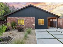 Charming single-story home with red brick and modern siding, a well-manicured yard, and a concrete driveway with grass accents at 358 E Whitton Ave, Phoenix, AZ 85012
