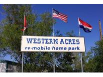 Sign at Western Acres RV-Mobile Home Park with welcoming flags in the background at 9913 E Main St # 40, Mesa, AZ 85207