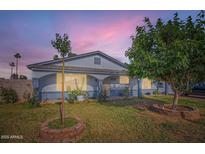 Charming single-story home featuring lush green lawn and mature trees enhancing its curb appeal at dusk at 1657 N 55Th Ave, Phoenix, AZ 85035