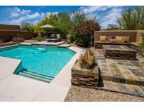 Inviting backyard pool with baja step, waterfall feature, and outdoor seating around a stacked stone fire pit at 8502 E Cave Creek Rd # 61, Carefree, AZ 85377