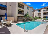 Community pool with clear blue water, lounge chairs, and palm trees near an apartment building with private balconies at 16631 E El Lago Blvd # 212, Fountain Hills, AZ 85268