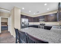 Stylish kitchen featuring dark cabinets, stainless steel appliances, and a granite countertop island at 2049 N 77Th Dr, Phoenix, AZ 85035