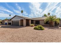 A desert-landscaped single-Gathering home featuring a brick facade, a metal awning, and a large palm tree in the front yard at 3106 S Extension Rd, Mesa, AZ 85210