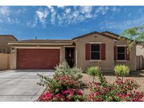 Charming single-story home featuring a red garage door, desert landscaping, and a cozy front porch at 8715 W Agora Ln, Tolleson, AZ 85353